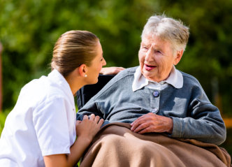 caregiver holding hands with senior women sitting in wheelchair